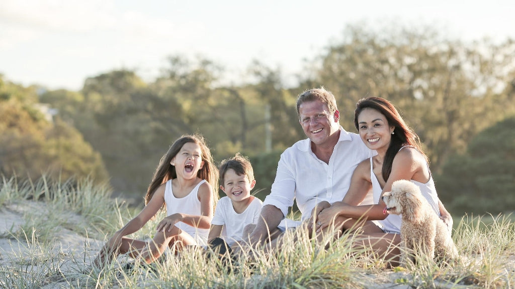 Familie mit zwei Kindern sitzt auf Wiese